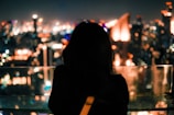 Silhouette of a woman against a glowing neon cityscape backdrop.