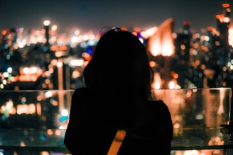 Nighttime city skyline blurred behind a figure dressed in luminous outerwear.