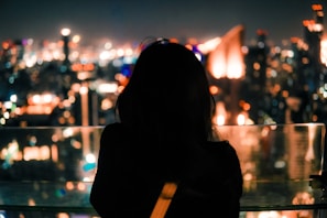 Silhouette of a woman against a glowing neon cityscape backdrop.