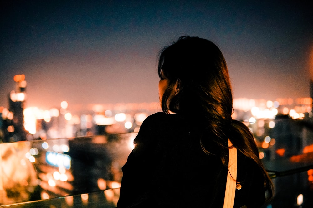 uma mulher olhando para uma cidade à noite