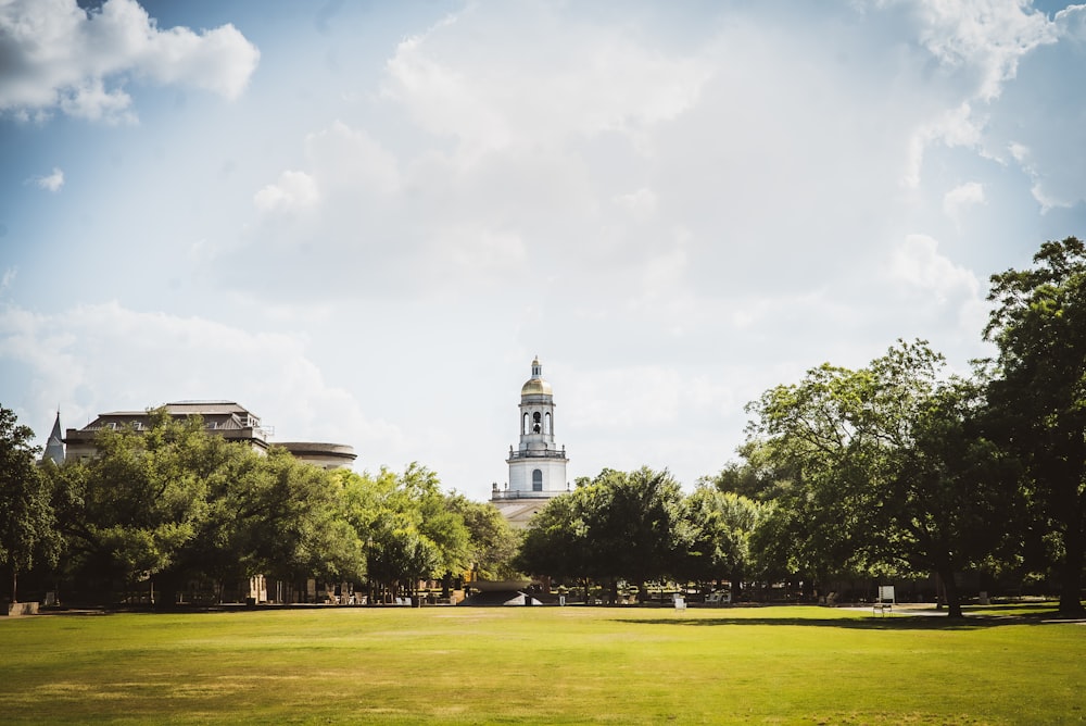 a large grassy field with a clock tower in the background