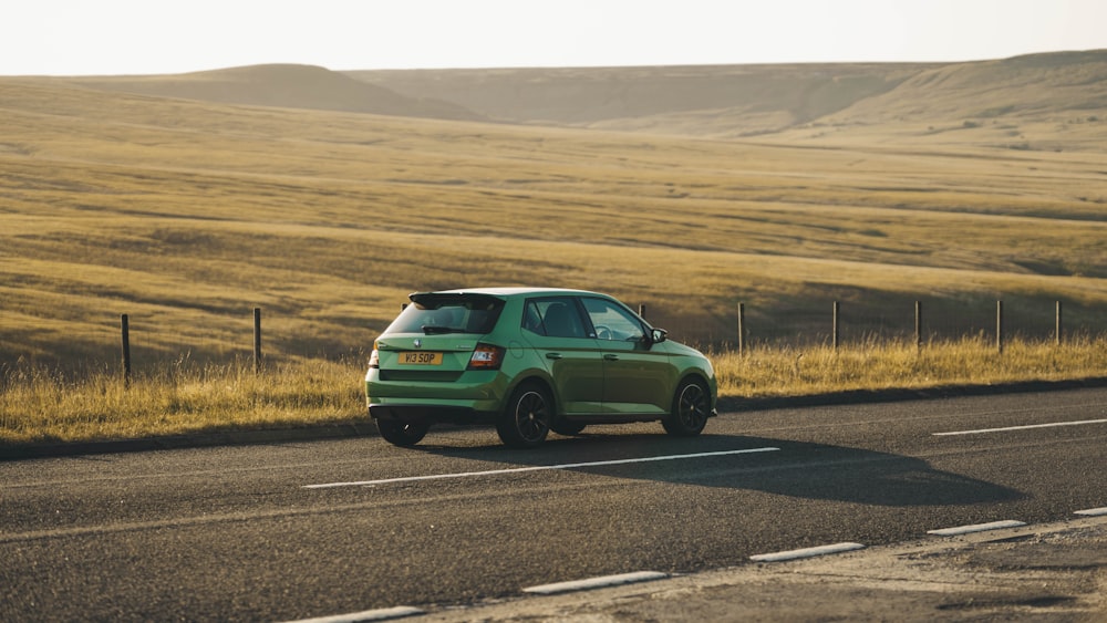 a green car is driving down the road