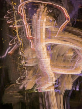 Light trails and abstract patterns create an energetic and chaotic visual effect with vibrant lines of varying colors and thicknesses. The movement and blend of colors result in a dynamic composition.