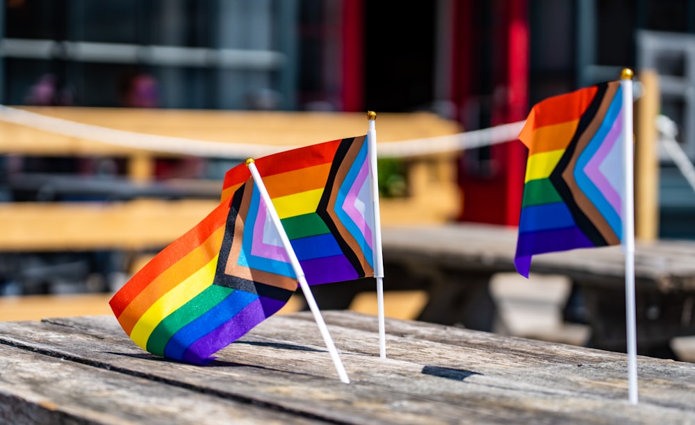 two rainbow flags sitting on top of a wooden table
