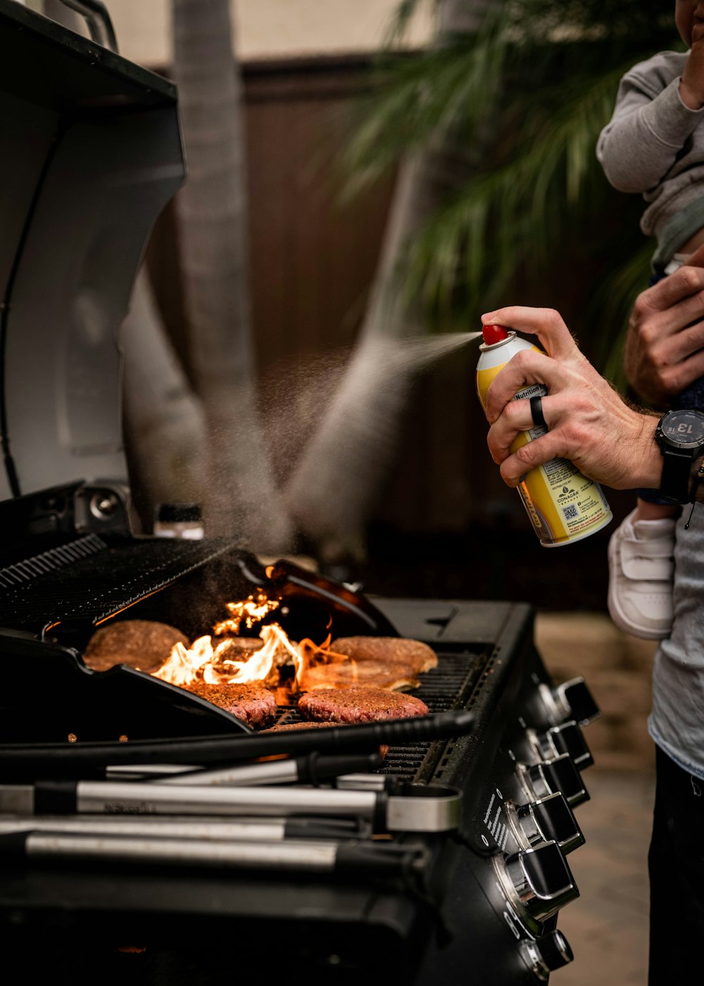 a man holding a baby while cooking on a grill