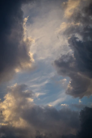 a plane flying through a cloudy blue sky