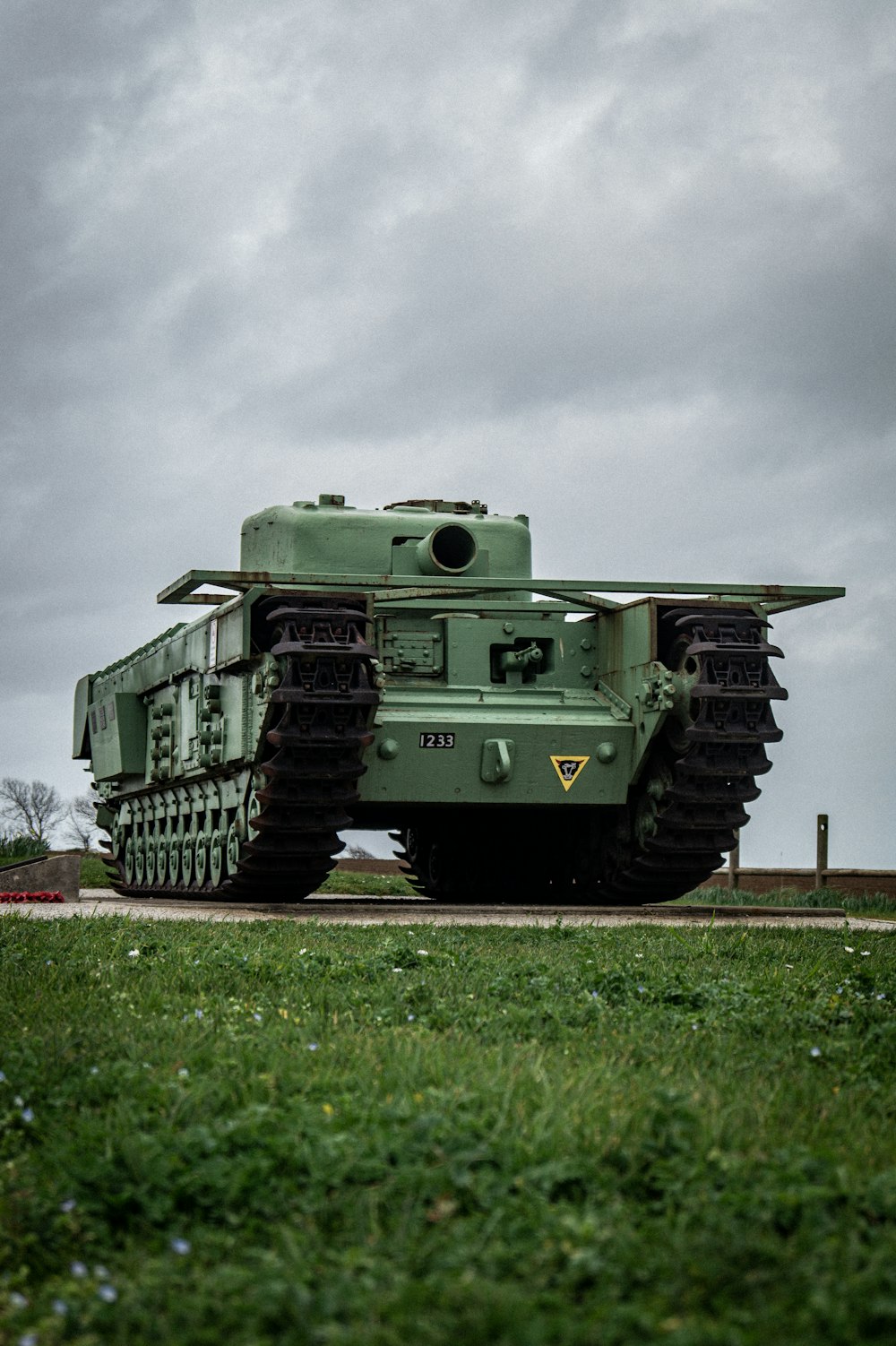 a large green tank sitting on top of a lush green field