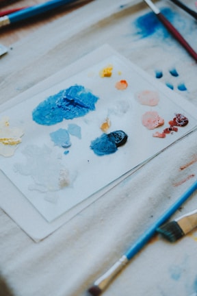 a table topped with lots of paint and brushes