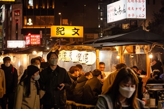 A bustling street food market at night, glowing with lanterns and filled with smiling faces.