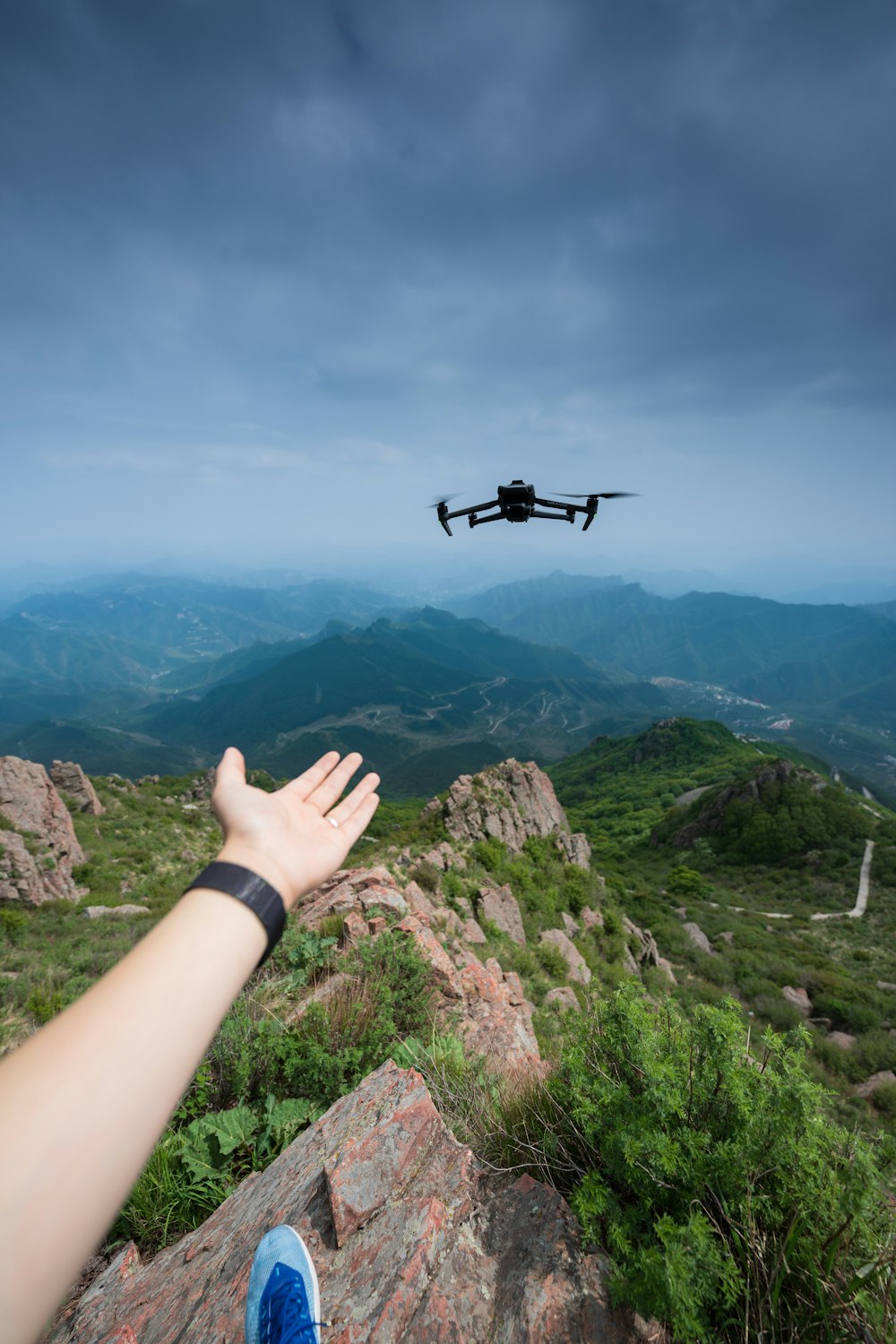 a person reaching out to a remote control plane in the sky