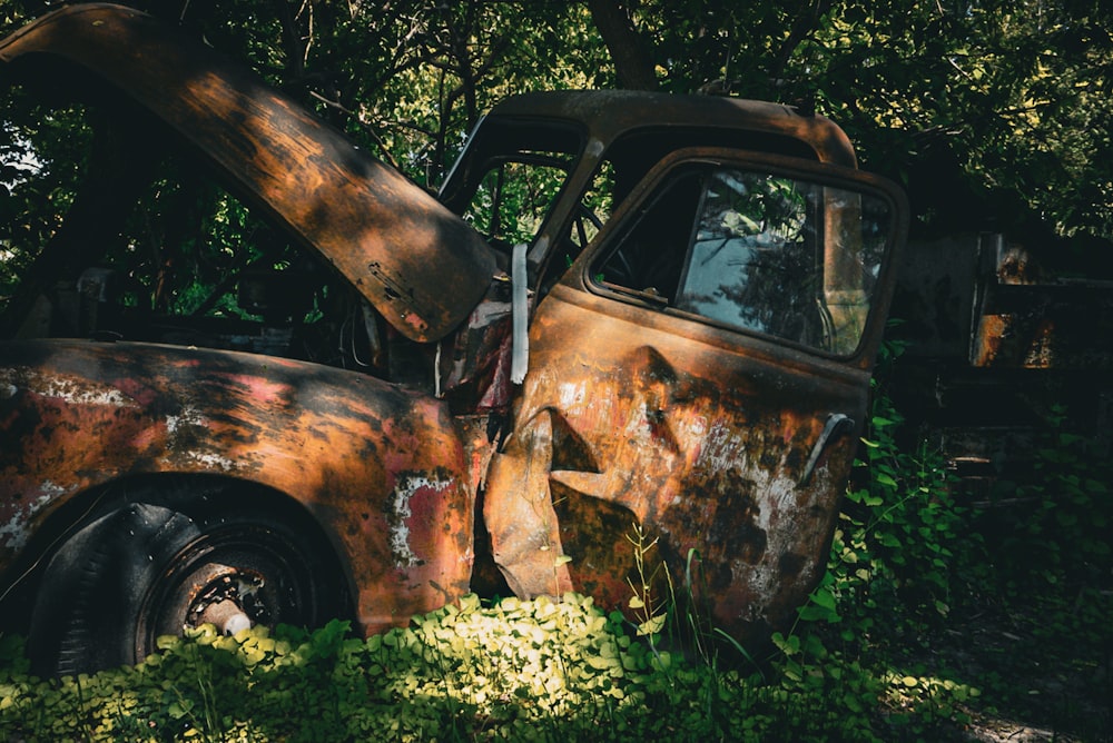 an old rusted truck sitting in the grass