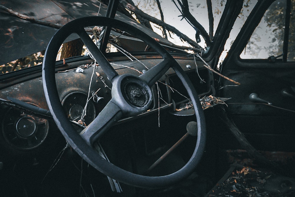 an old car with a steering wheel in a junkyard