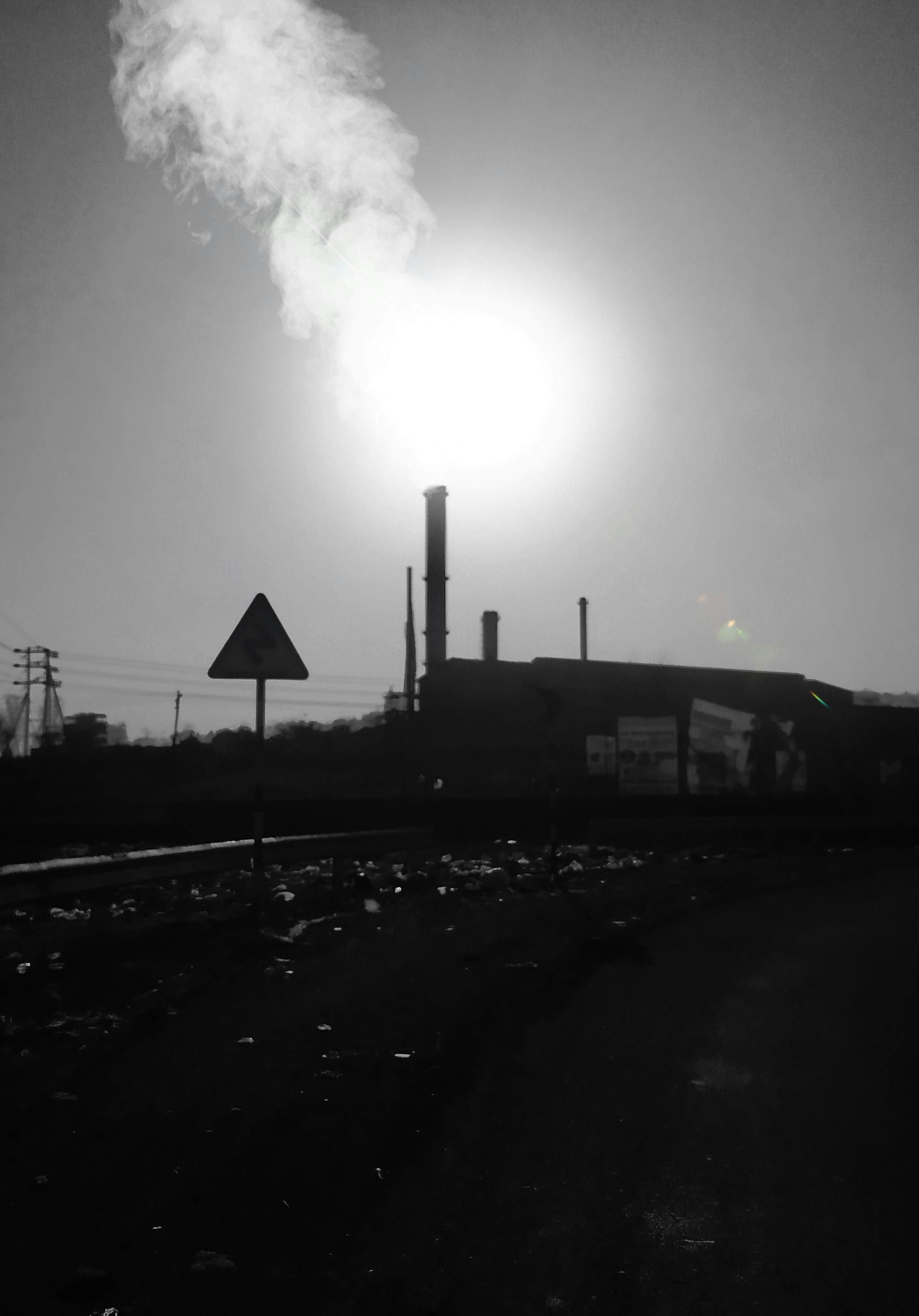a black and white photo of smoke coming out of a factory