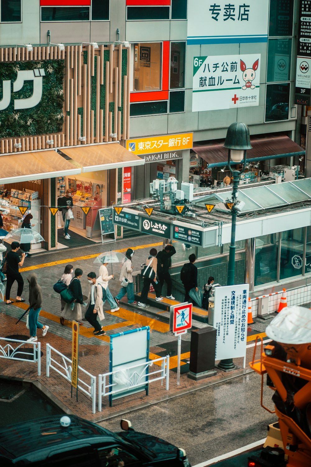 a group of people walking down a street next to tall buildings