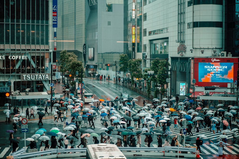 a crowd of people with umbrellas crossing a street