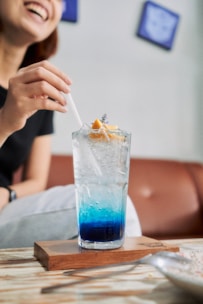 a woman sitting at a table with a drink in front of her