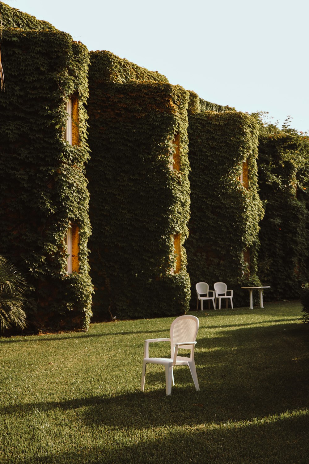 a white lawn chair sitting in the middle of a lush green lawn
