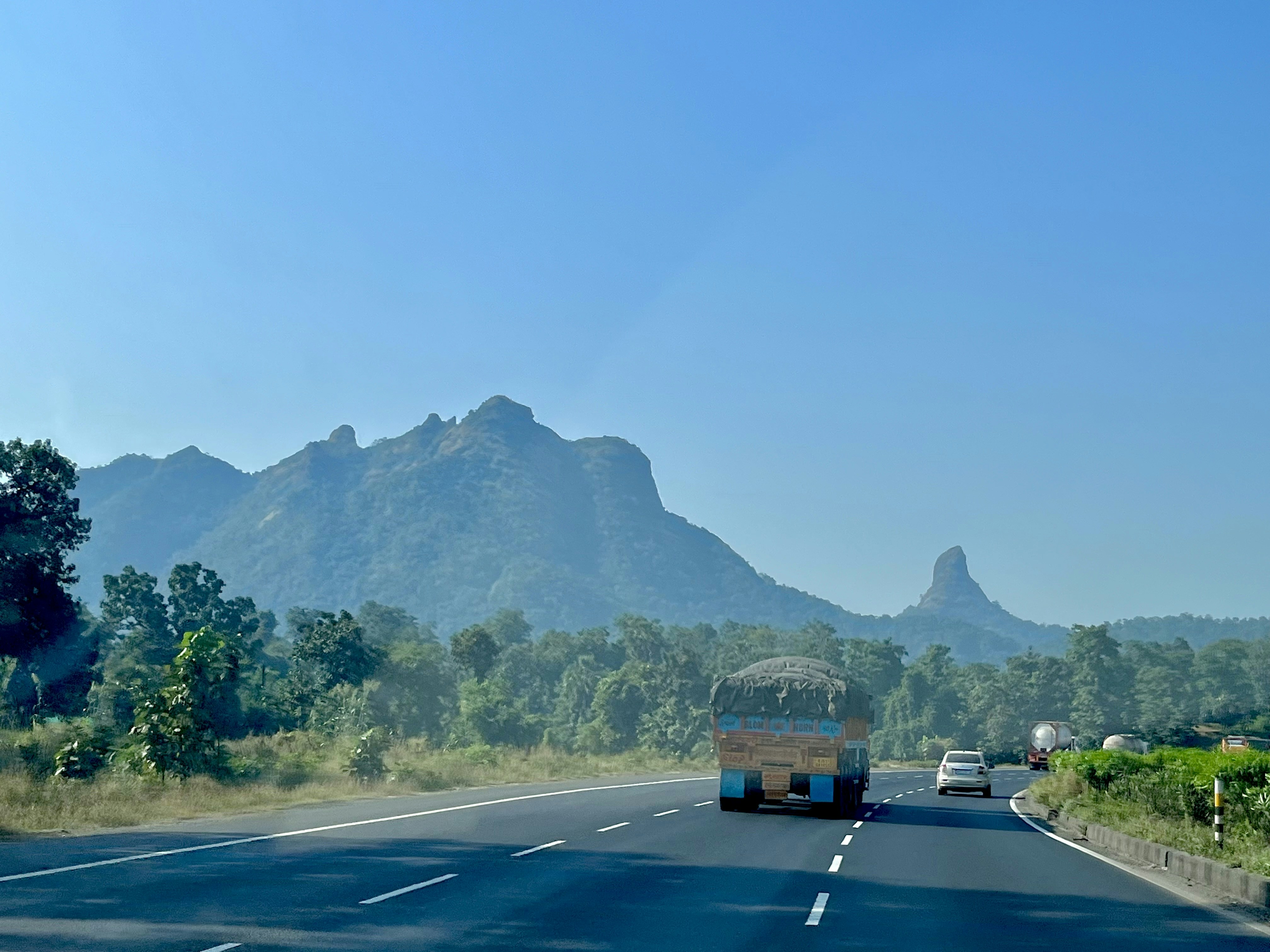 a bus driving down a road with mountains in the background