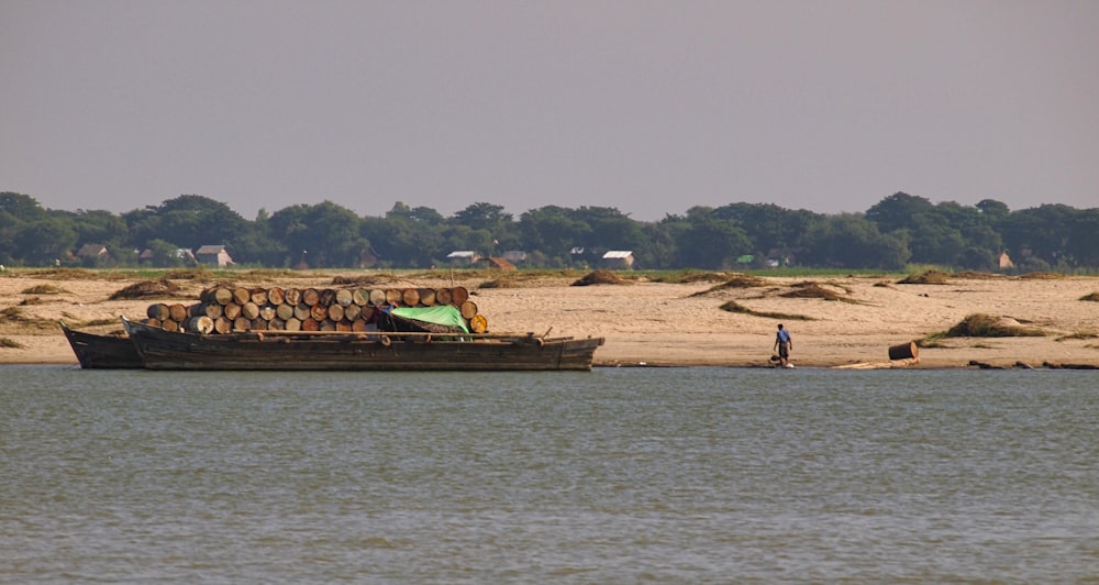 a boat filled with logs sitting on top of a lake