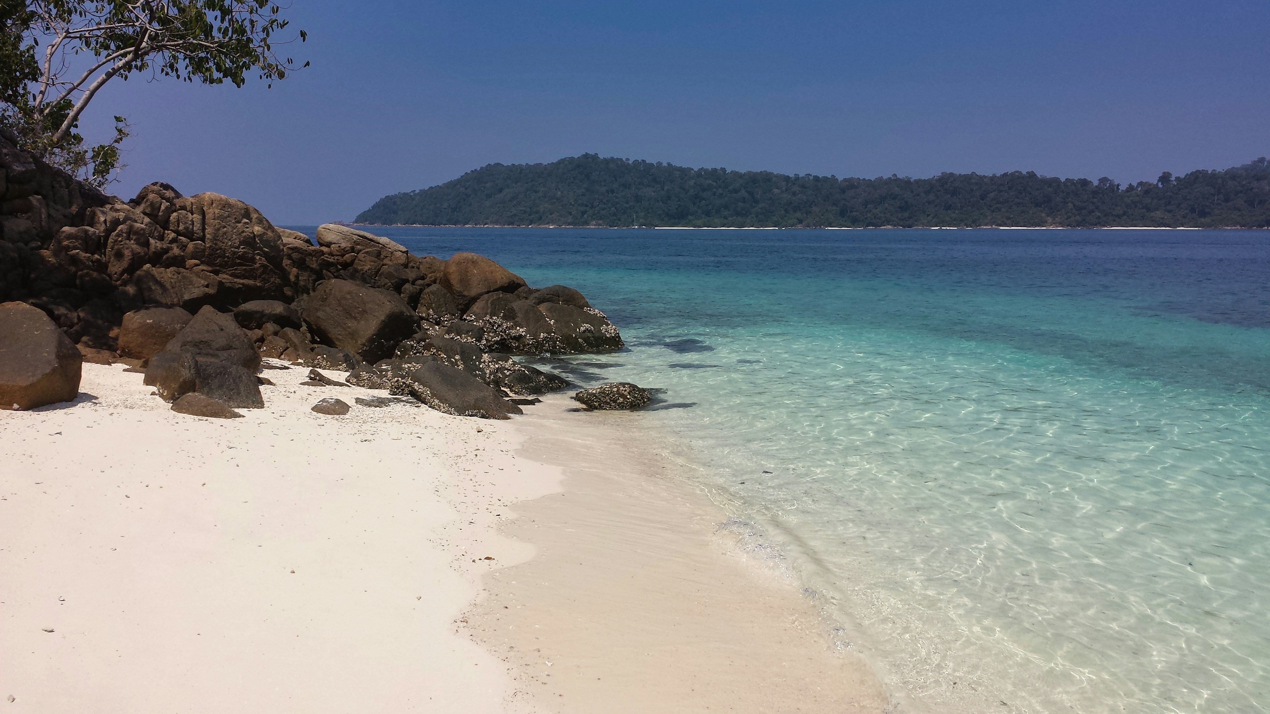 a sandy beach with clear blue water and rocks, Ko Ra Wi, Satun Thailand January 29 2015: Ko Ra Wi Beach, Southern Thailand - A slice of paradise with talcum-like white sand caressed by turquoise waves. Pure bliss.