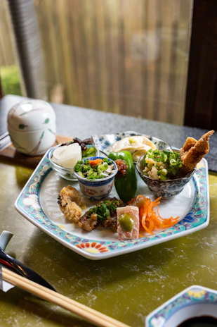 Close-up of a textured Japanese-style plate with delicate patterns, holding a beautifully arranged meal.