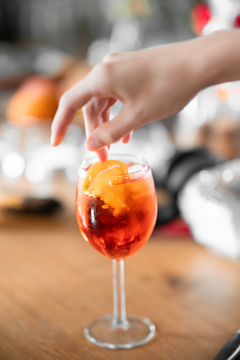 a person reaching for an orange in a wine glass