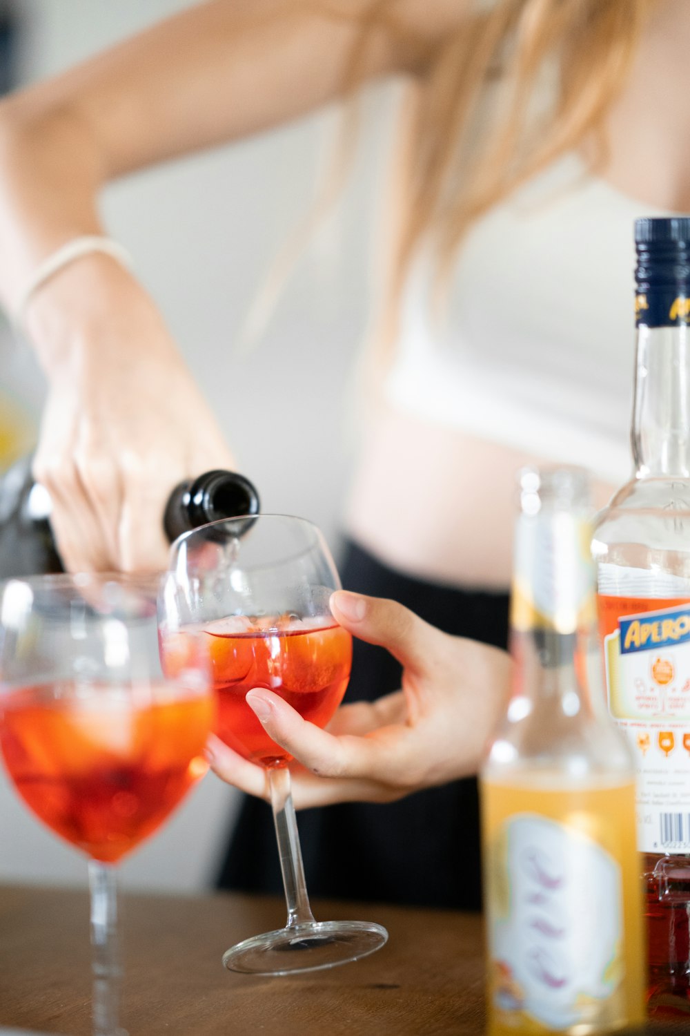 a woman pouring a drink into a glass