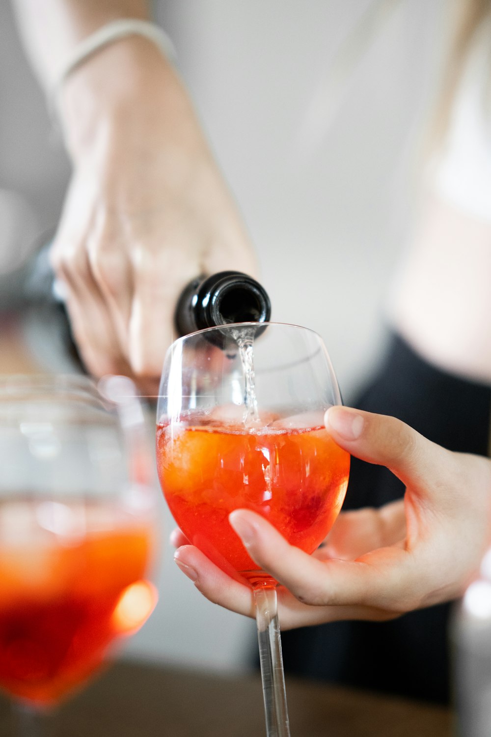 a person pouring a drink into a wine glass