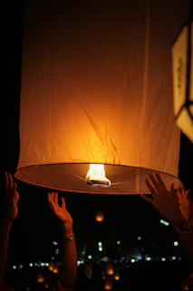 Hands releasing glowing lanterns into a twilight sky, symbolizing hope and spiritual freedom