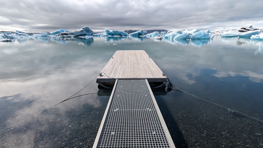 a dock in the middle of a body of water with icebergs in the