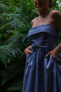a woman in a blue dress standing in a forest