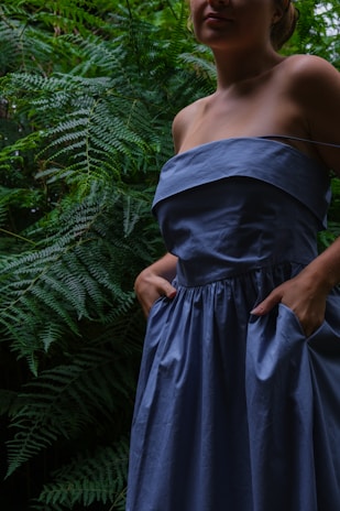 a woman in a blue dress standing in a forest