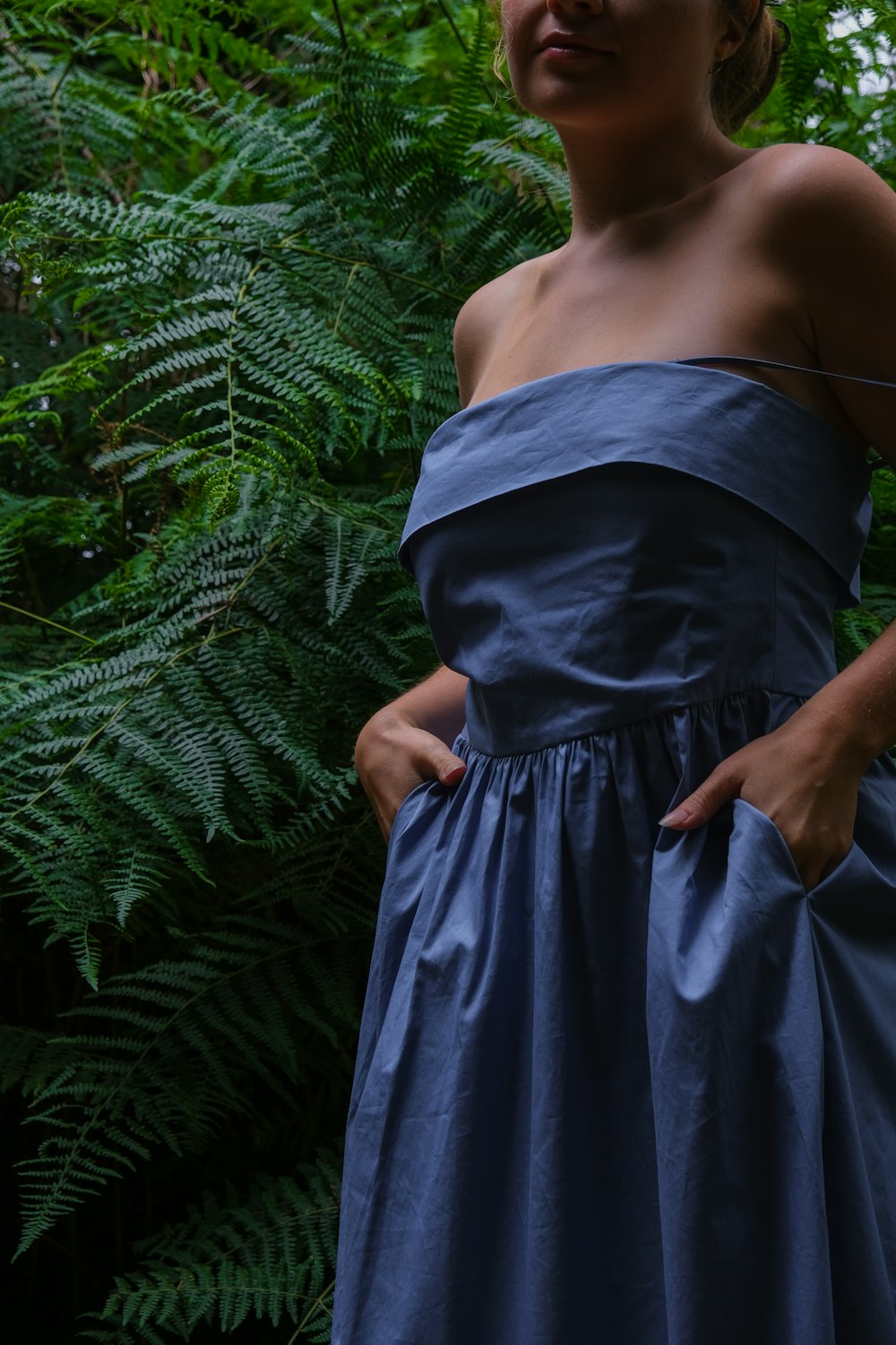 eine frau in einem blauen kleid, die in einem wald steht