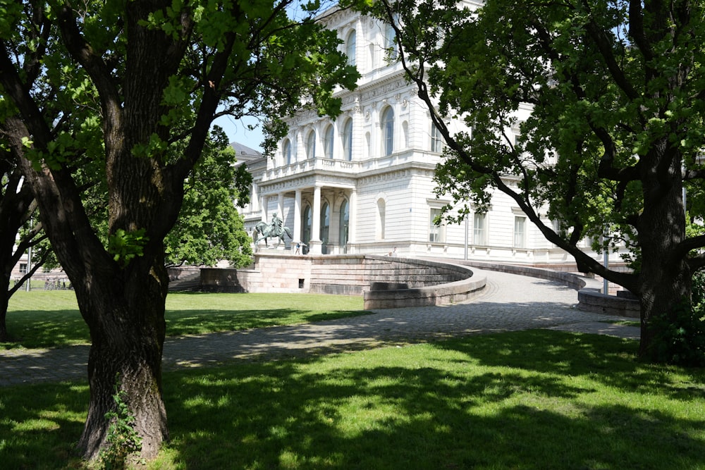 a large white building sitting next to a lush green park