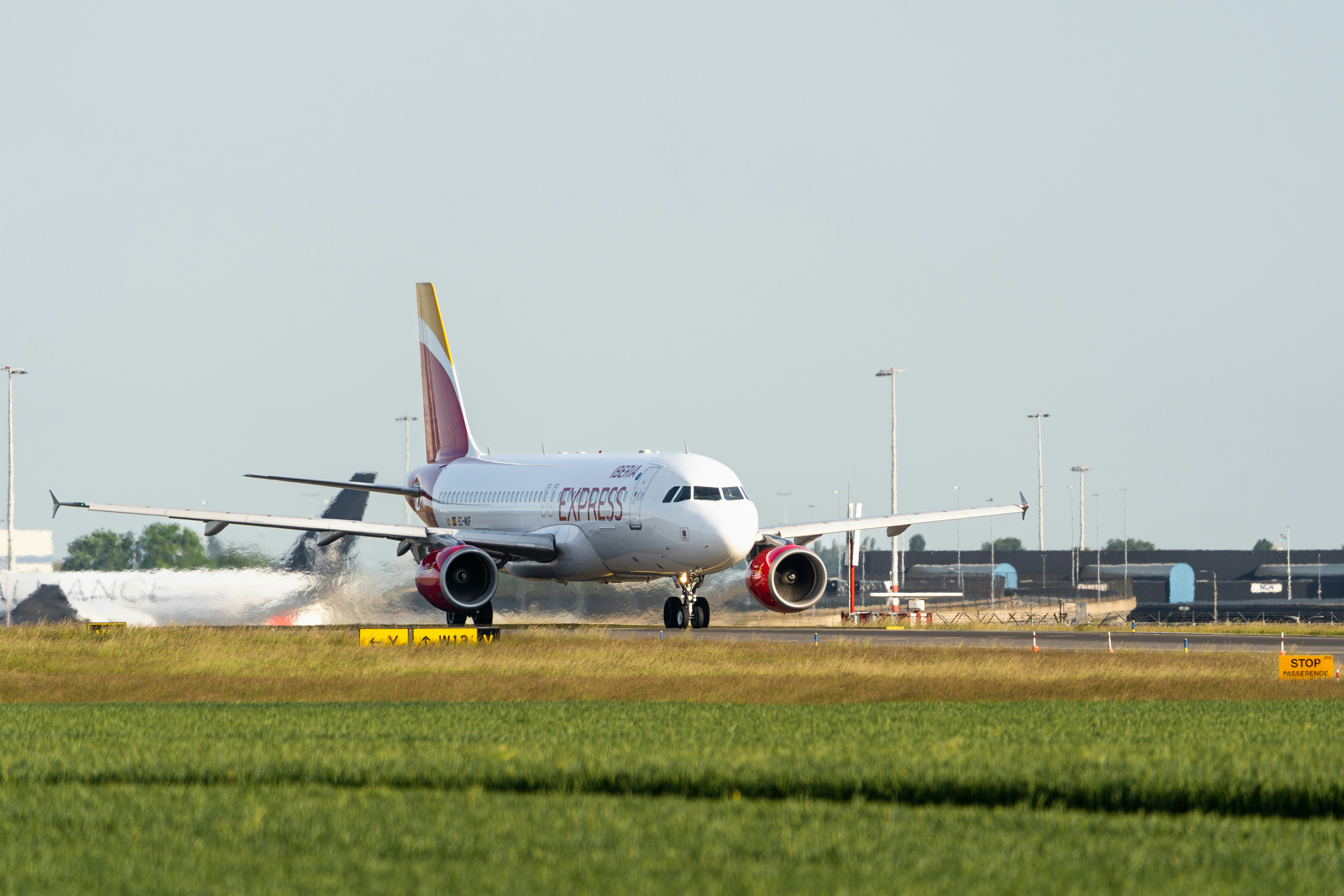 a large jetliner sitting on top of an airport runway, Iberia Express flight IB3725 to Madrid (an Airbus A320-214, reg. EC-MUF) taxiing to the Polderbaan runway at Schiphol airport for departure.