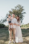 a man and woman holding a baby in a field