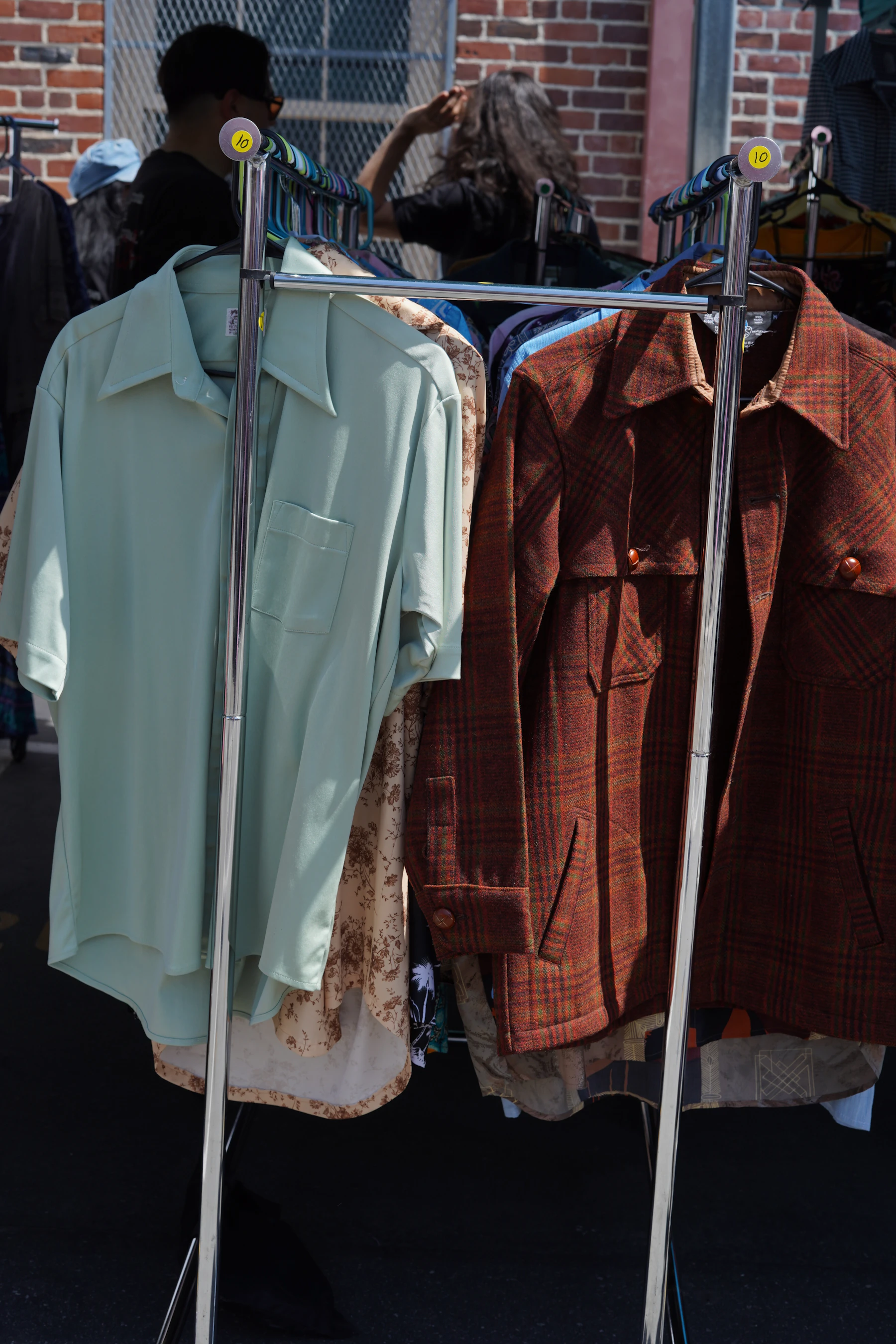 a rack of clothing on a street with a brick building in the background