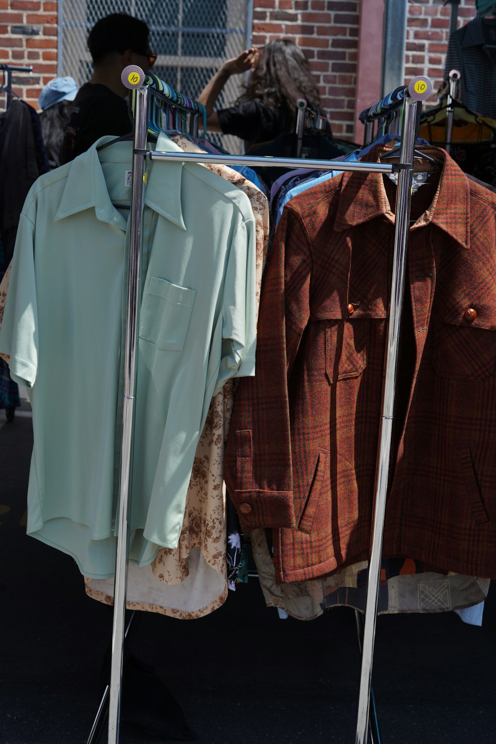 a rack of clothing on a street with a brick building in the background