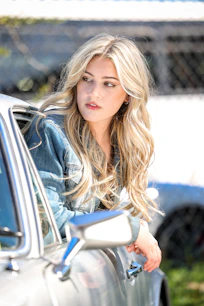 a woman leaning on the door of a car
