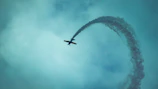 Pilot Adam Gibbs performing a daring loop with smoke trailing behind.