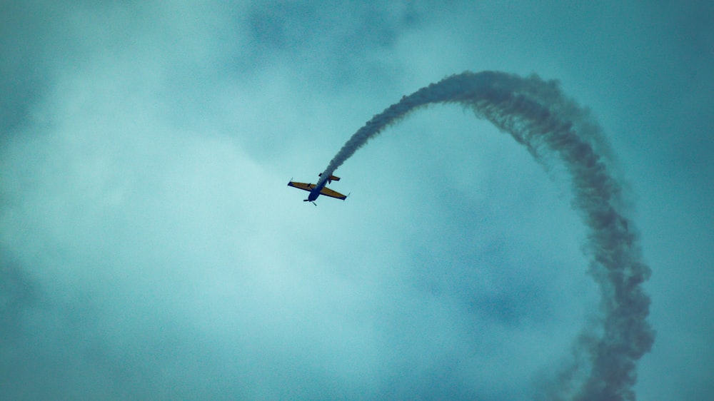 an airplane flying in the sky with a smoke trail behind it