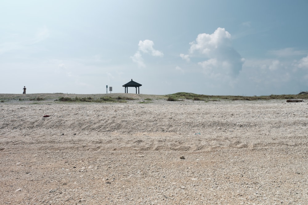 a gazebo on a sandy beach under a blue sky