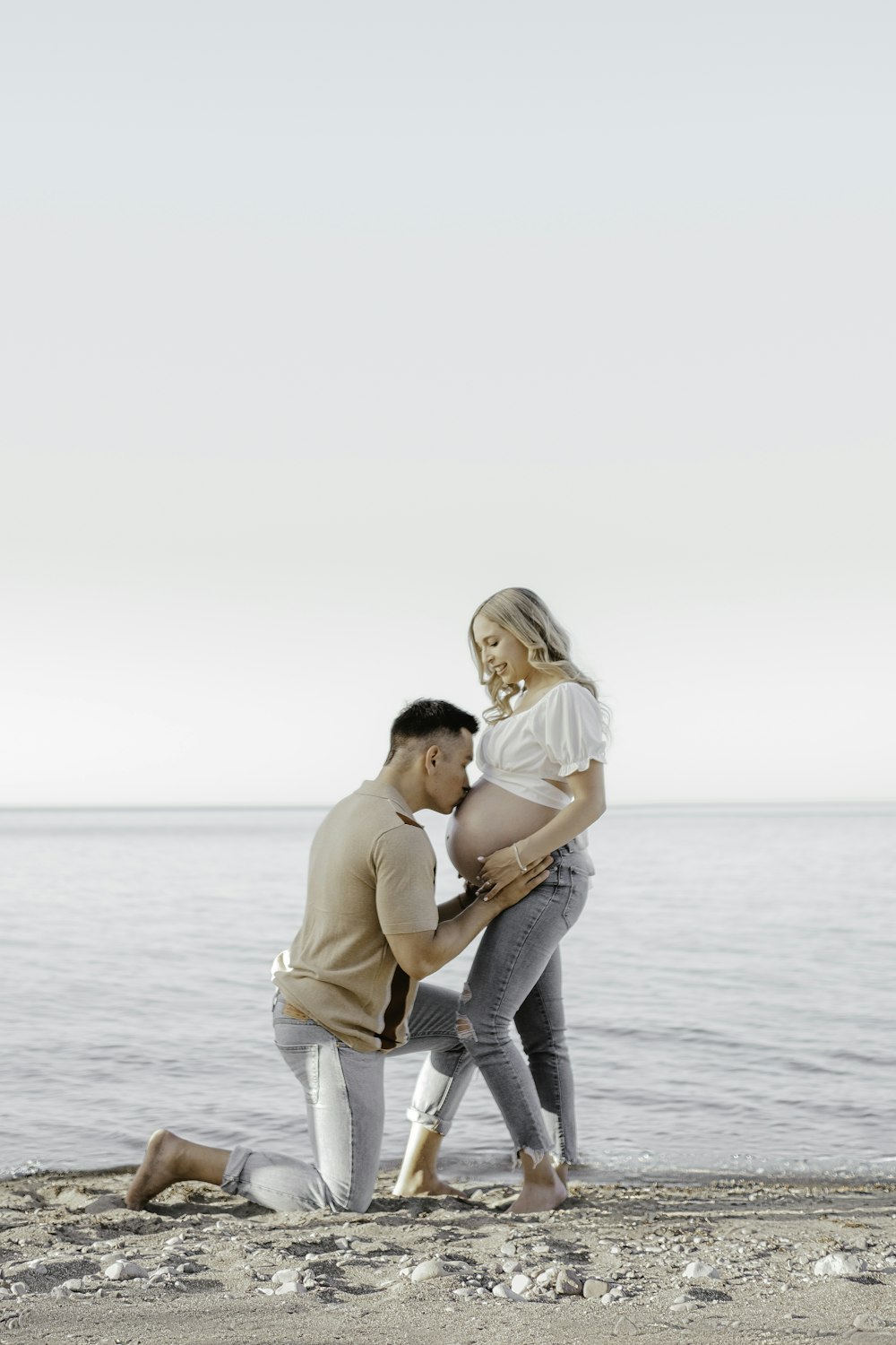 a man and woman standing on a beach next to the ocean