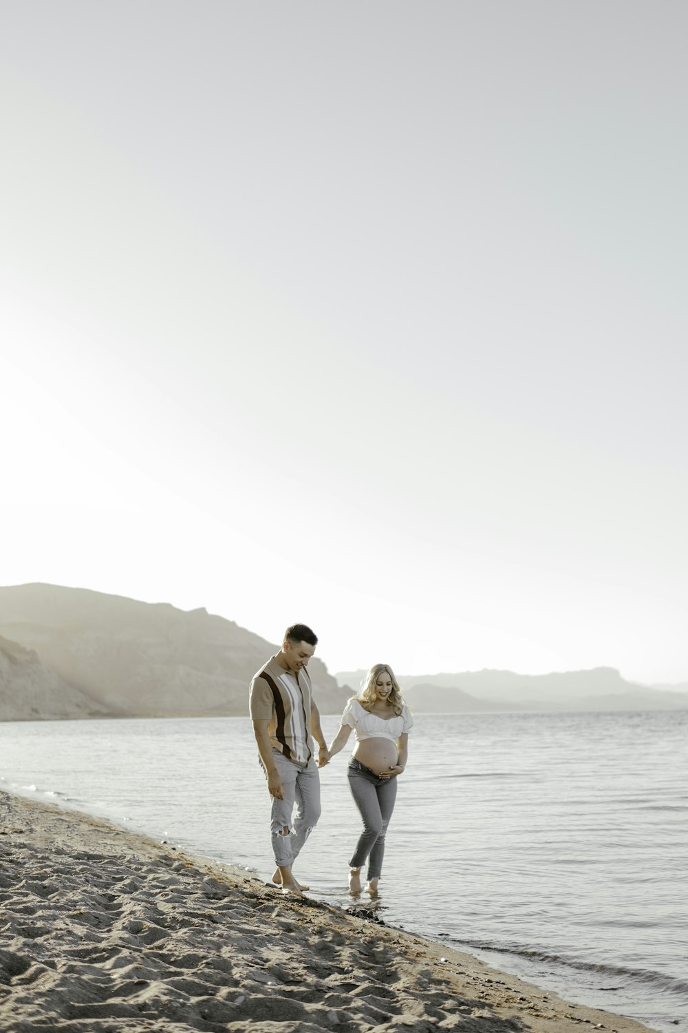 um homem e uma mulher caminhando ao longo de uma praia