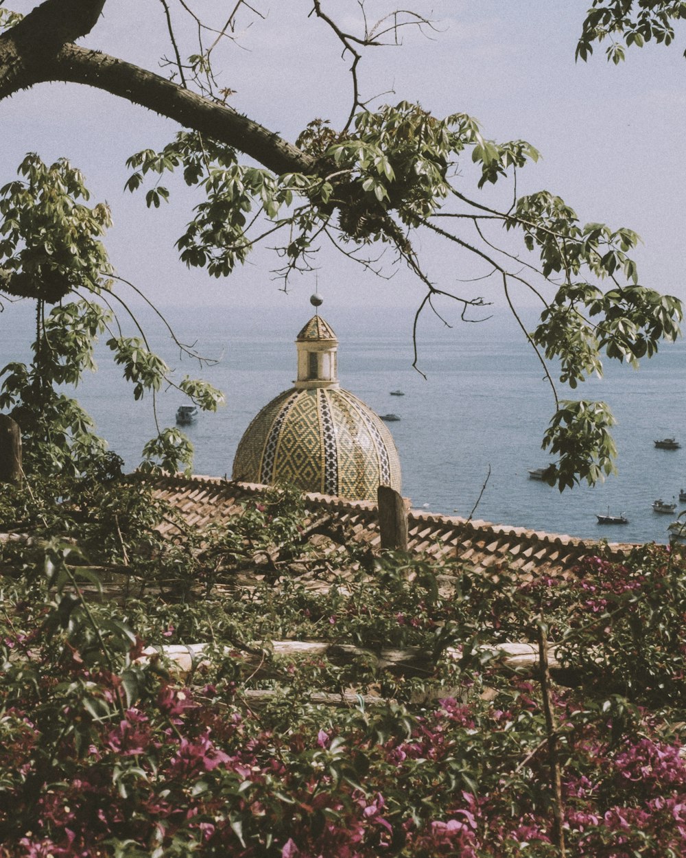 a building with a dome sitting on top of a lush green hillside