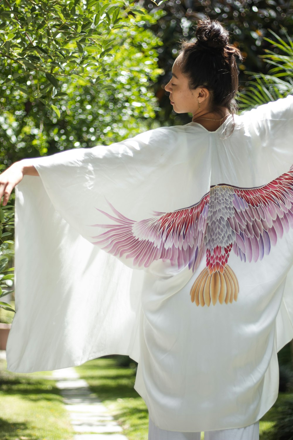 una mujer con un kimono blanco con un pájaro pintado en él