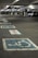 A multi-level parking garage featuring painted handicap parking symbols on the ground. Several cars are parked in the background, with the area dimly lit by overhead lights. Concrete pillars and signs denote parking sections.