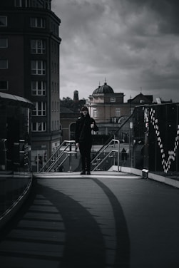 A moody urban scene featuring a man wearing layered dark streetwear with sharp, avant-garde details.