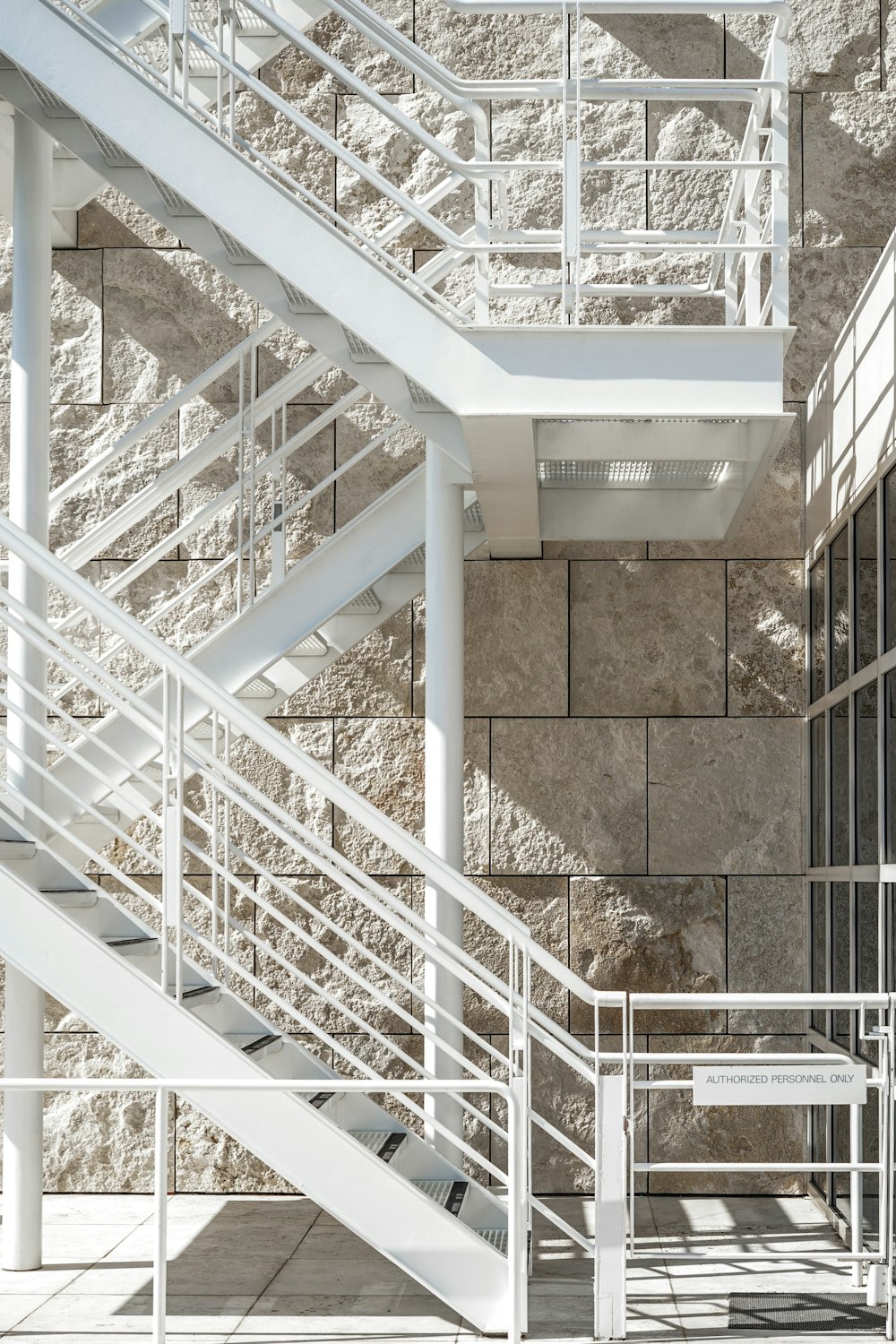 a white metal staircase next to a stone wall