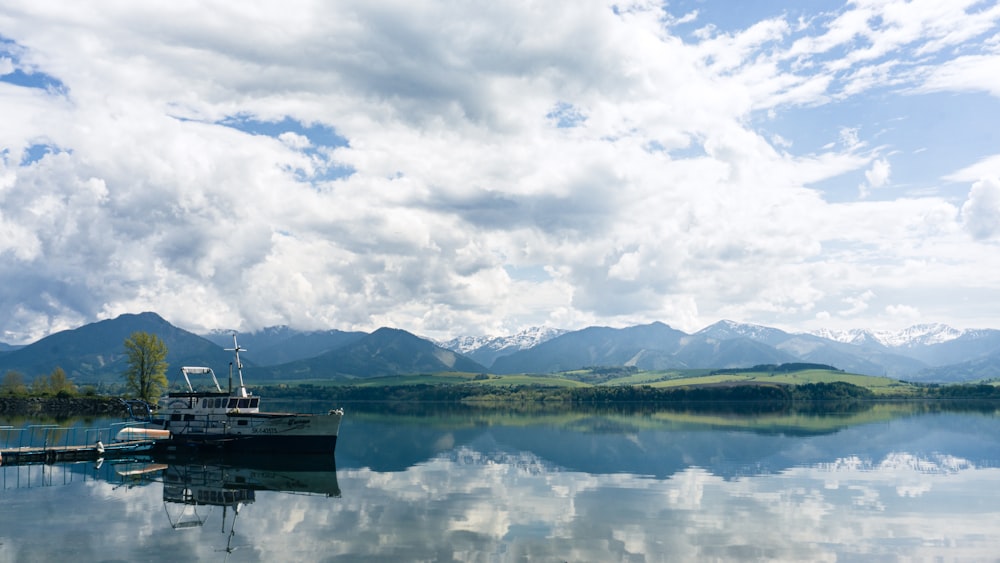 a boat is docked on a lake with mountains in the background